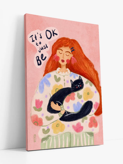 Canvas print with a woman holding a cat and 'It's OK to just be' text on a pink background