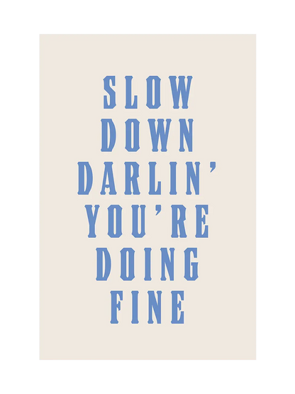 Типографски арт принт с надпис Slow Down Darlin’ You’re Doing Fine в светлосини букви върху топъл неутрален фон.